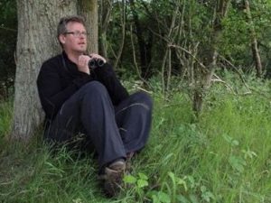 Wildlife Travel leader James Lowen sat bird watching by a tree